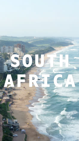 Vertical-Video-Drone-Shot-Of-Coastline-With-Ocean-And-Beach-Resort-Overlaid-With-Graphic-Spelling-Out-South-Africa